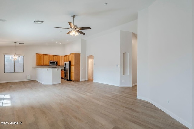 15853 N 74th Ave, Peoria, AZ 85382 - unfurnished living room featuring light wood finished floors, visible vents, baseboards, ceiling fan with notable chandelier, and arched walkways