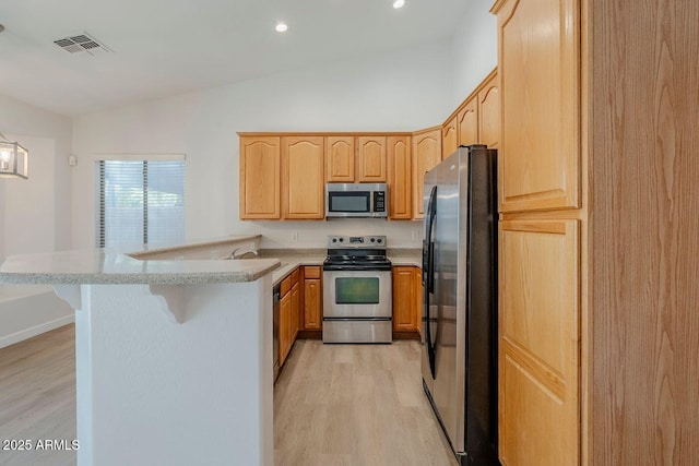 15853 N 74th Ave, Peoria, AZ 85382 - kitchen with light brown cabinets, visible vents, a peninsula, vaulted ceiling, and appliances with stainless steel finishes