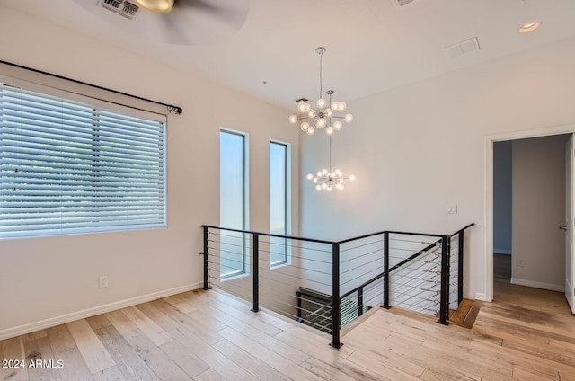 unfurnished room with a notable chandelier and light wood-type flooring