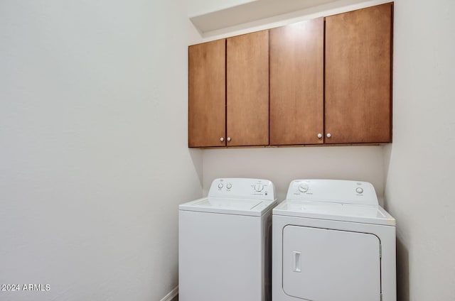 washroom with washing machine and clothes dryer and cabinets