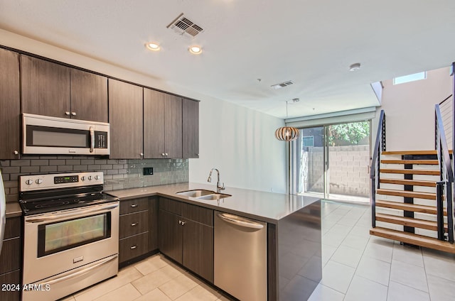 kitchen featuring dark brown cabinets, kitchen peninsula, sink, and appliances with stainless steel finishes