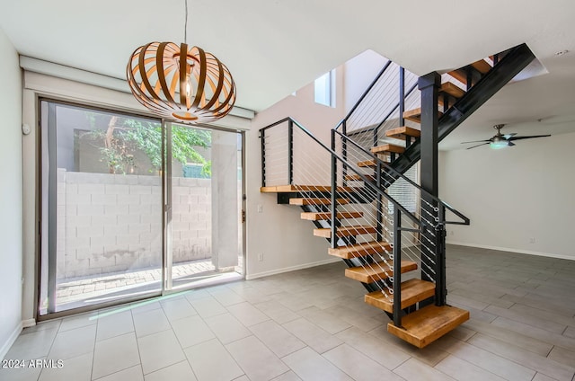 stairs featuring ceiling fan with notable chandelier