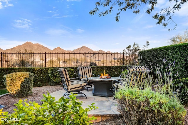 view of patio / terrace featuring an outdoor fire pit, fence, and a mountain view