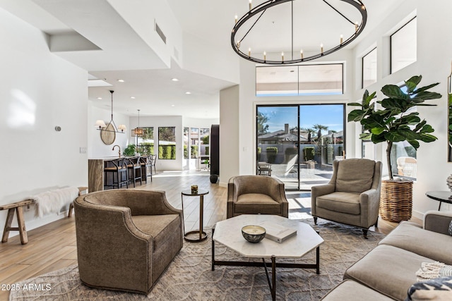 living room featuring sink, a towering ceiling, wood-type flooring, and a chandelier