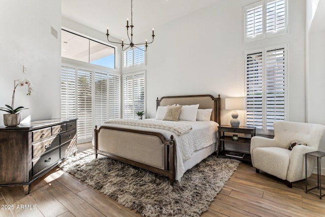 bedroom featuring multiple windows, a high ceiling, and hardwood / wood-style floors