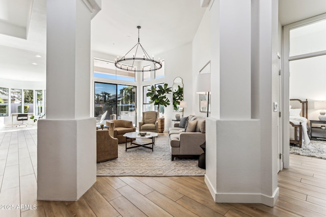 living room featuring light hardwood / wood-style flooring, a chandelier, and a high ceiling