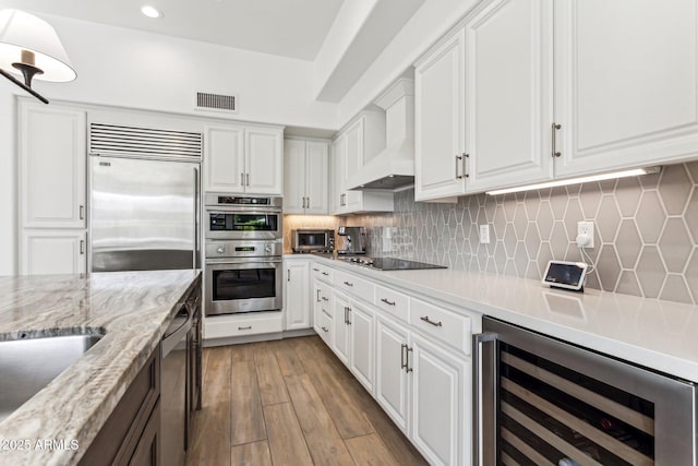 kitchen with backsplash, stainless steel appliances, wine cooler, white cabinets, and custom exhaust hood