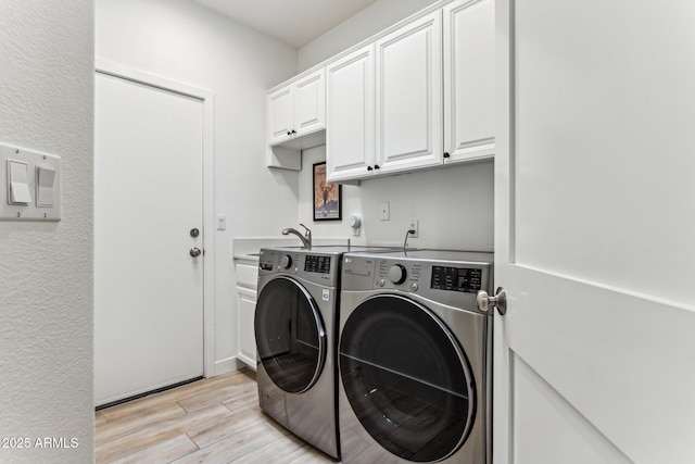 clothes washing area with separate washer and dryer, sink, light hardwood / wood-style flooring, and cabinets