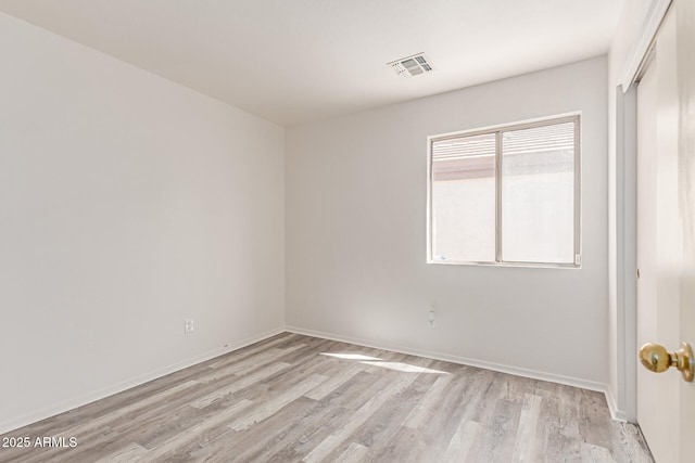 unfurnished room featuring light wood-style floors, baseboards, and visible vents
