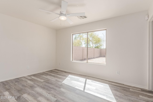 unfurnished room with visible vents, a ceiling fan, baseboards, and wood finished floors