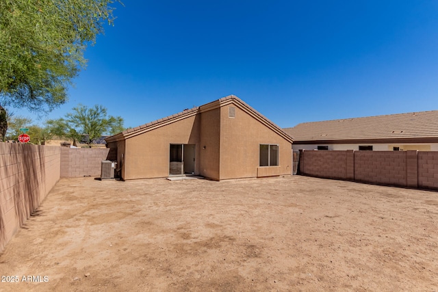 back of house with a fenced backyard, central air condition unit, and stucco siding