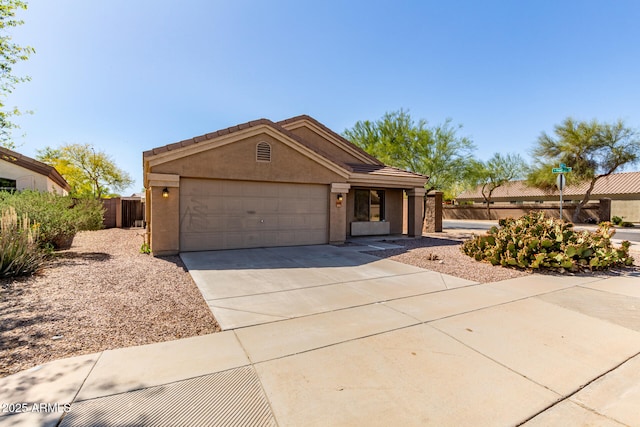 ranch-style house with a tiled roof, fence, concrete driveway, an attached garage, and stucco siding