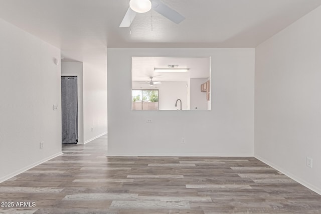 empty room featuring baseboards, ceiling fan, and wood finished floors