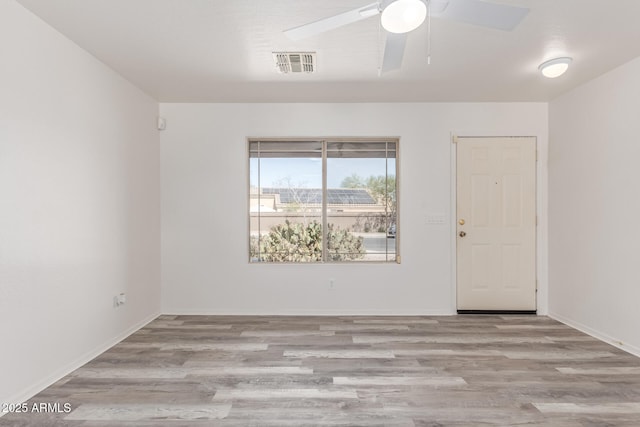 unfurnished room featuring visible vents, a ceiling fan, baseboards, and wood finished floors