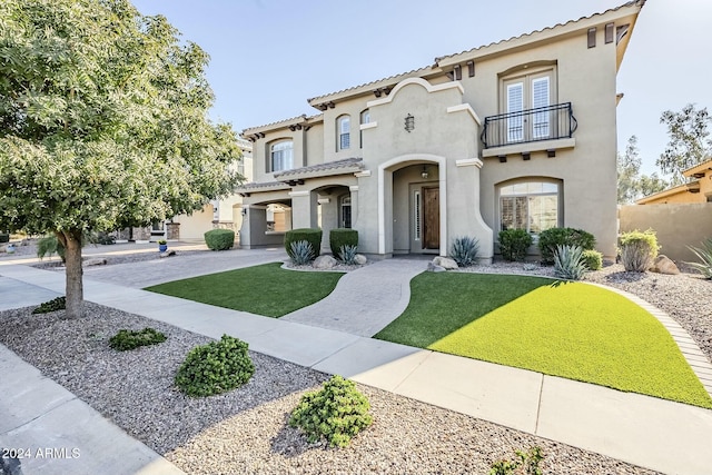 mediterranean / spanish-style house with a front yard, french doors, and a balcony