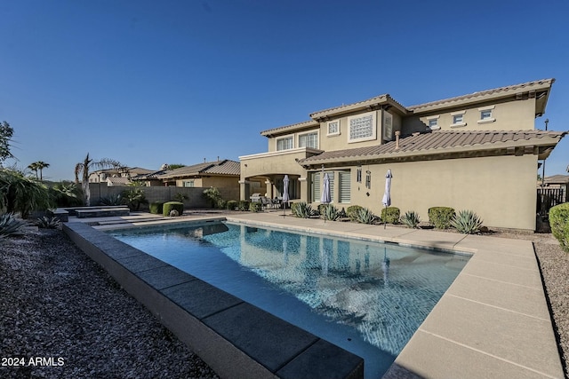 rear view of property featuring a fenced in pool and a patio area