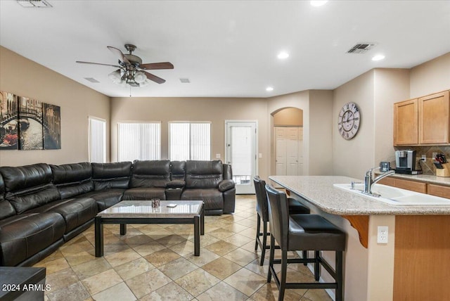 living area with arched walkways, visible vents, ceiling fan, and recessed lighting