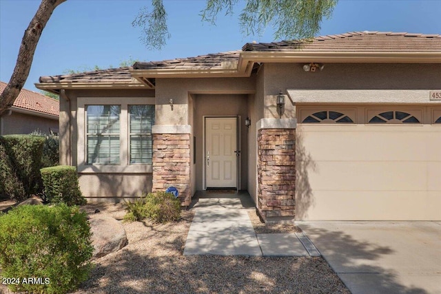 view of front of house with a garage, stone siding, a tile roof, and stucco siding