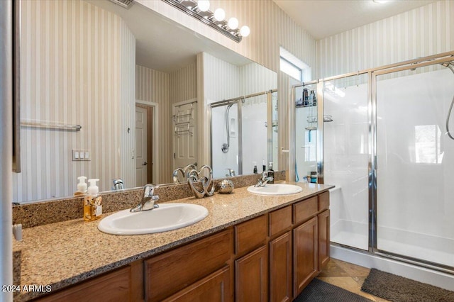 bathroom with a stall shower, a sink, and wallpapered walls