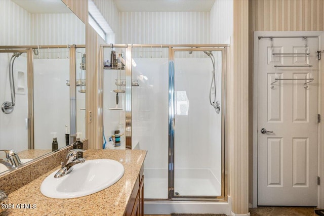 full bath with a shower stall, vanity, and wallpapered walls