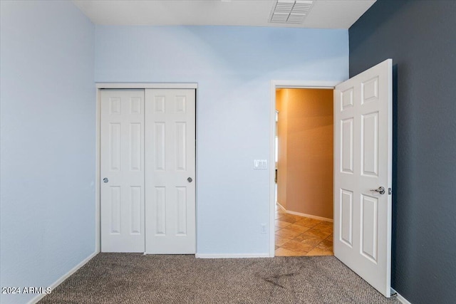 unfurnished bedroom featuring baseboards, carpet, visible vents, and a closet