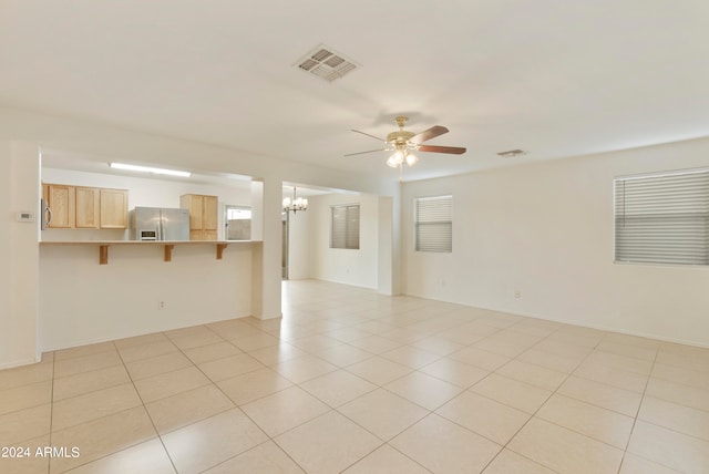 empty room featuring light tile patterned floors and ceiling fan with notable chandelier