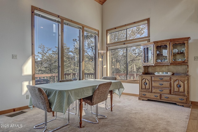 carpeted dining space with a towering ceiling