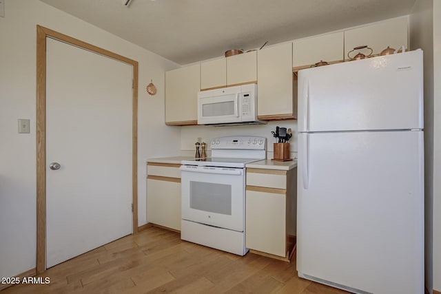 kitchen with light wood-type flooring, white appliances, and cream cabinetry