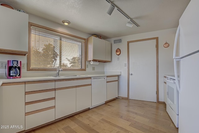 kitchen with white cabinetry, white appliances, light hardwood / wood-style floors, and sink