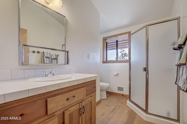 bathroom with hardwood / wood-style flooring, vanity, toilet, and an enclosed shower