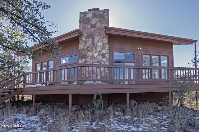 snow covered back of property with a wooden deck