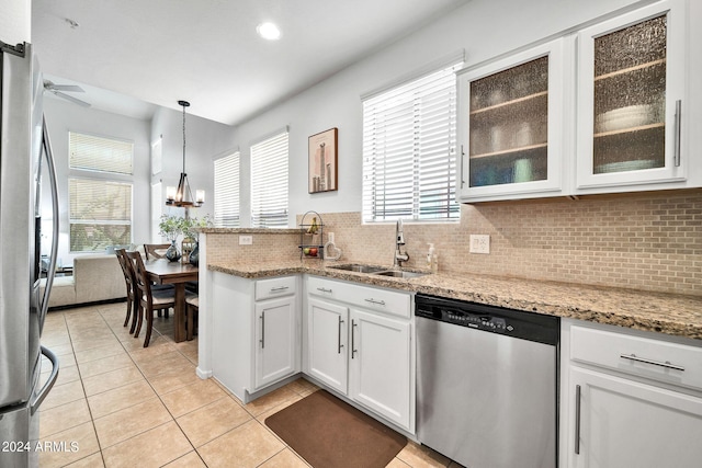 kitchen featuring pendant lighting, sink, appliances with stainless steel finishes, light stone countertops, and white cabinets