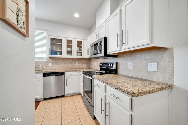 kitchen with appliances with stainless steel finishes, white cabinetry, backsplash, light tile patterned floors, and light stone countertops