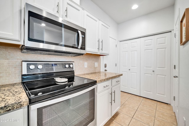 kitchen with white cabinetry, appliances with stainless steel finishes, light stone countertops, and light tile patterned floors