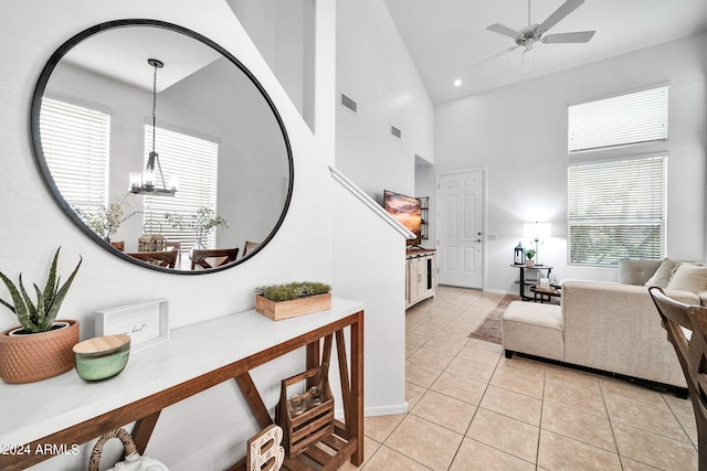 interior space featuring ceiling fan with notable chandelier, light tile patterned floors, and high vaulted ceiling