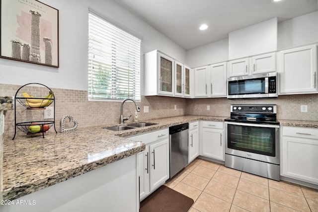 kitchen featuring sink, light tile patterned floors, appliances with stainless steel finishes, white cabinetry, and light stone countertops