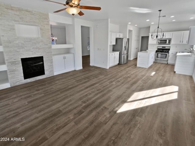 kitchen with a fireplace, appliances with stainless steel finishes, decorative light fixtures, and white cabinetry