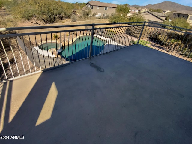 balcony with a mountain view, a patio area, and an in ground hot tub