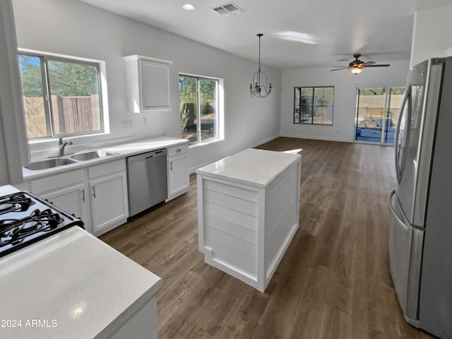 kitchen featuring appliances with stainless steel finishes, sink, decorative light fixtures, a center island, and white cabinetry