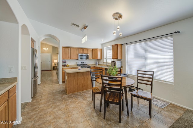 4369 E Coal St, San Tan Valley, AZ 85143 - kitchen featuring stainless steel appliances, arched walkways, a kitchen island, light countertops, and brown cabinets