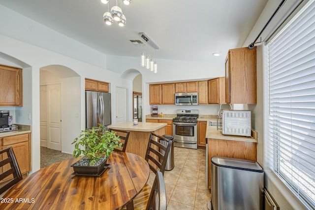 4369 E Coal St, San Tan Valley, AZ 85143 - kitchen featuring appliances with stainless steel finishes, arched walkways, light countertops, a kitchen island, and lofted ceiling