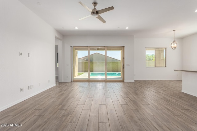 20499 W Alsap Rd, Buckeye, AZ 85396 - unfurnished living room with wood finished floors, ceiling fan, recessed lighting, baseboards, and a chandelier