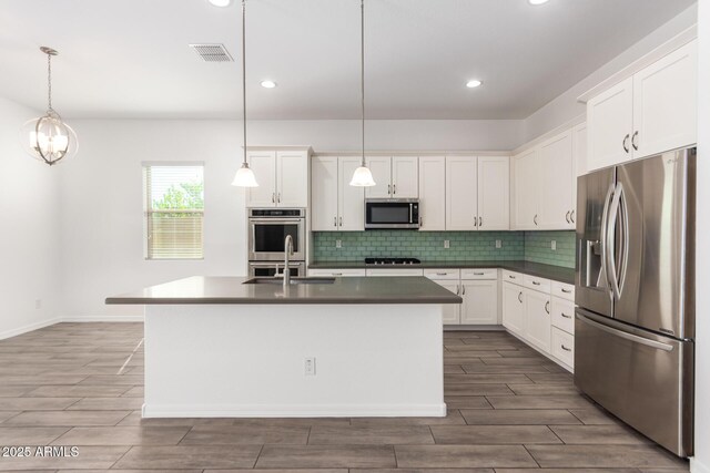 20499 W Alsap Rd, Buckeye, AZ 85396 - kitchen with stainless steel appliances, a sink, wood tiled floors, backsplash, and dark countertops