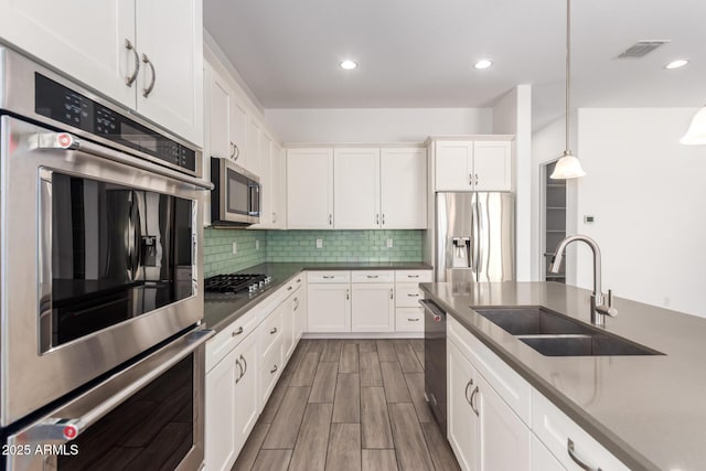 20499 W Alsap Rd, Buckeye, AZ 85396 - kitchen with appliances with stainless steel finishes, a sink, white cabinetry, tasteful backsplash, and decorative light fixtures