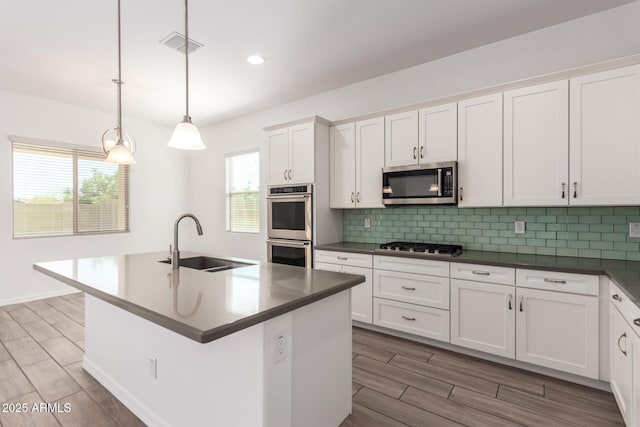 20499 W Alsap Rd, Buckeye, AZ 85396 - kitchen with stainless steel appliances, a sink, wood tiled floors, decorative backsplash, and white cabinets