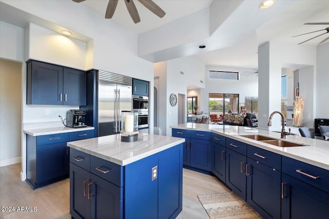 kitchen with blue cabinets, a center island, sink, and ceiling fan