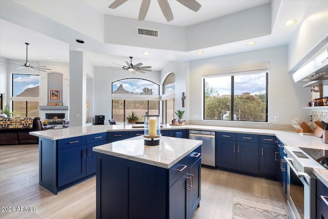 kitchen with ceiling fan, appliances with stainless steel finishes, a fireplace, and a kitchen island