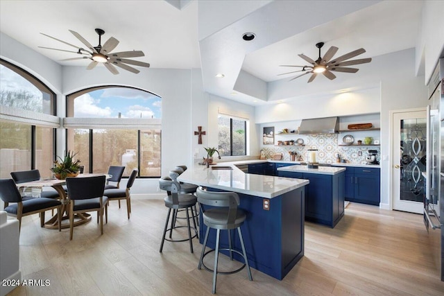 kitchen with ceiling fan, a kitchen bar, blue cabinets, and kitchen peninsula