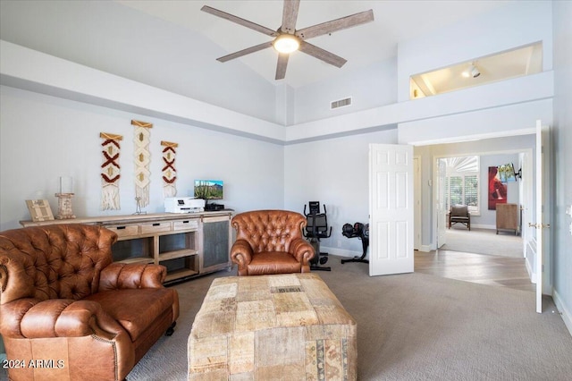 living room with light carpet, a towering ceiling, and ceiling fan