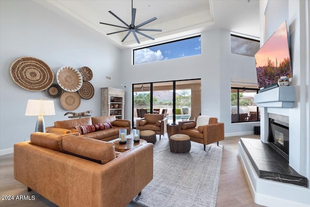 living room with light wood-type flooring, a high ceiling, and ceiling fan